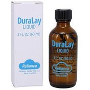 مایع آکریل دورالی ریلانس Reliance Duralay Liquid | بطری شیشه‌ای یا پلاستیکی شفاف با برچسب قرمز و برند Reliance آمریکا، کنار ظرف پودر قرمز دورالی و ابزار کار قالبگیری، زمینه سفید | panamal.ir